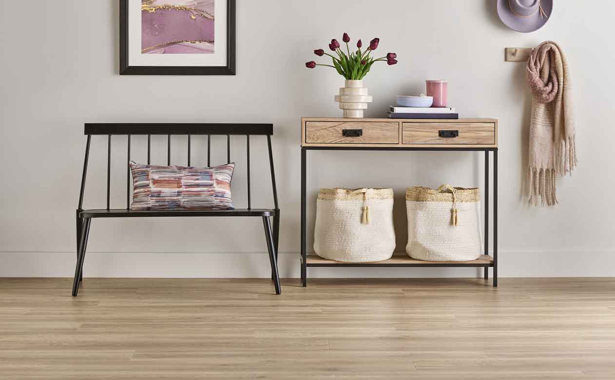 light wood look laminate flooring in entryway hallway with black bench and wood entry way table